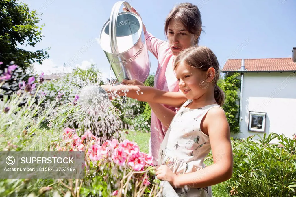 Mother and daughter in garden watering flowers