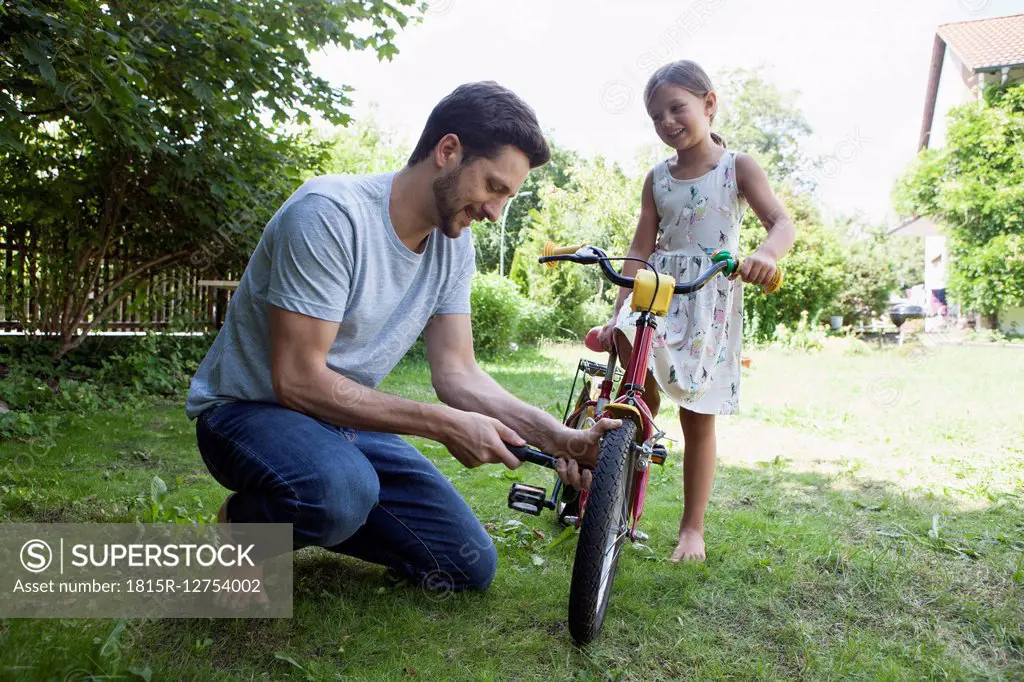 Father inflating daughter's bicycle
