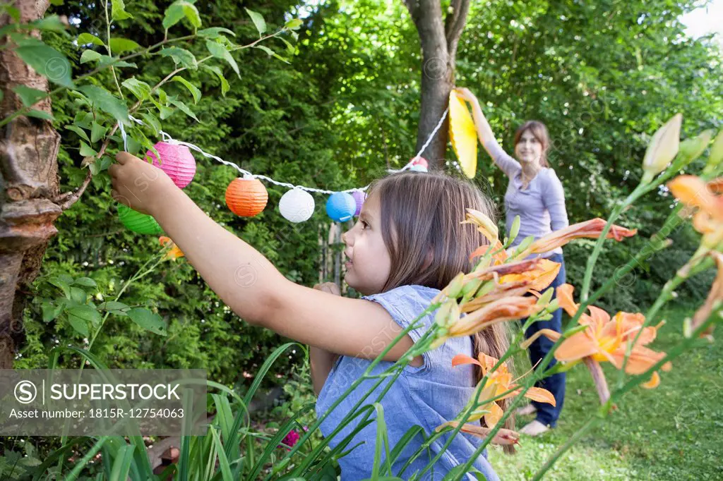 Mother and daughter hanging up a garland in garden