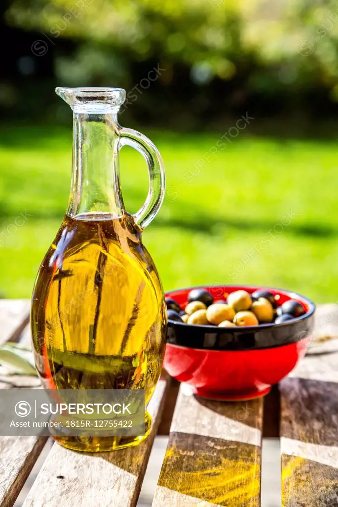 Bowl with green and black olives and carafe of olive oil