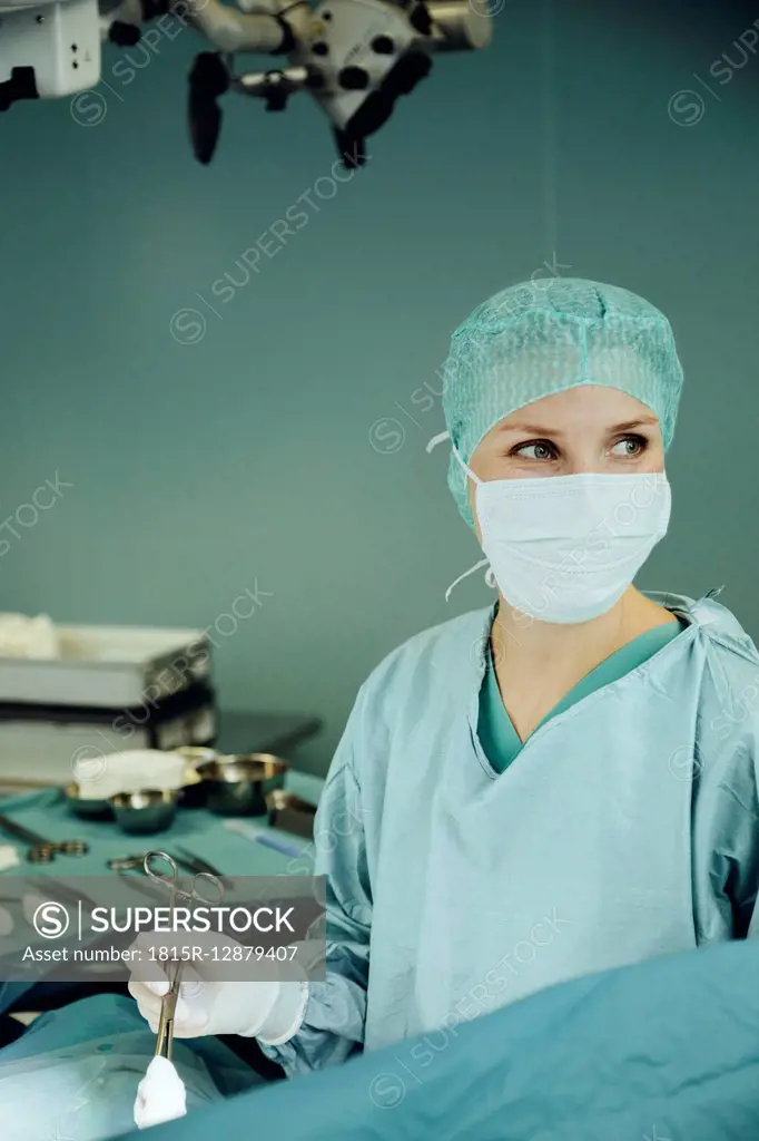 Female surgeon holding clamp in operating room during surgery