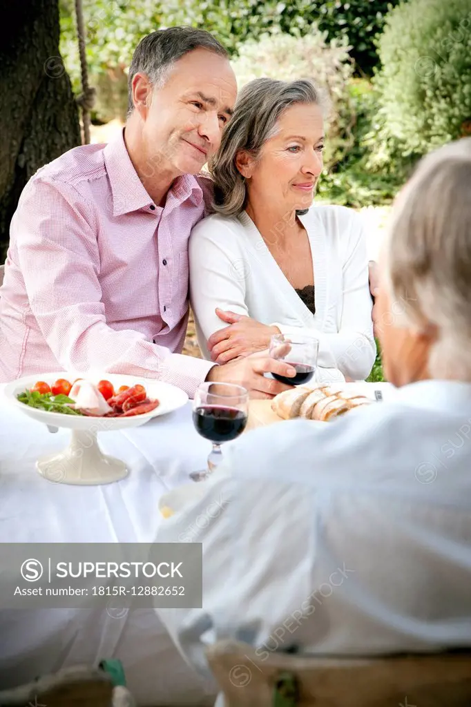 Portrait of mature couple sitting side by side at laid table in the garden