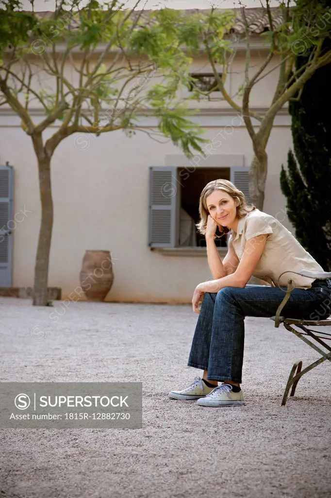 Smiling woman sitting on chair outdoors