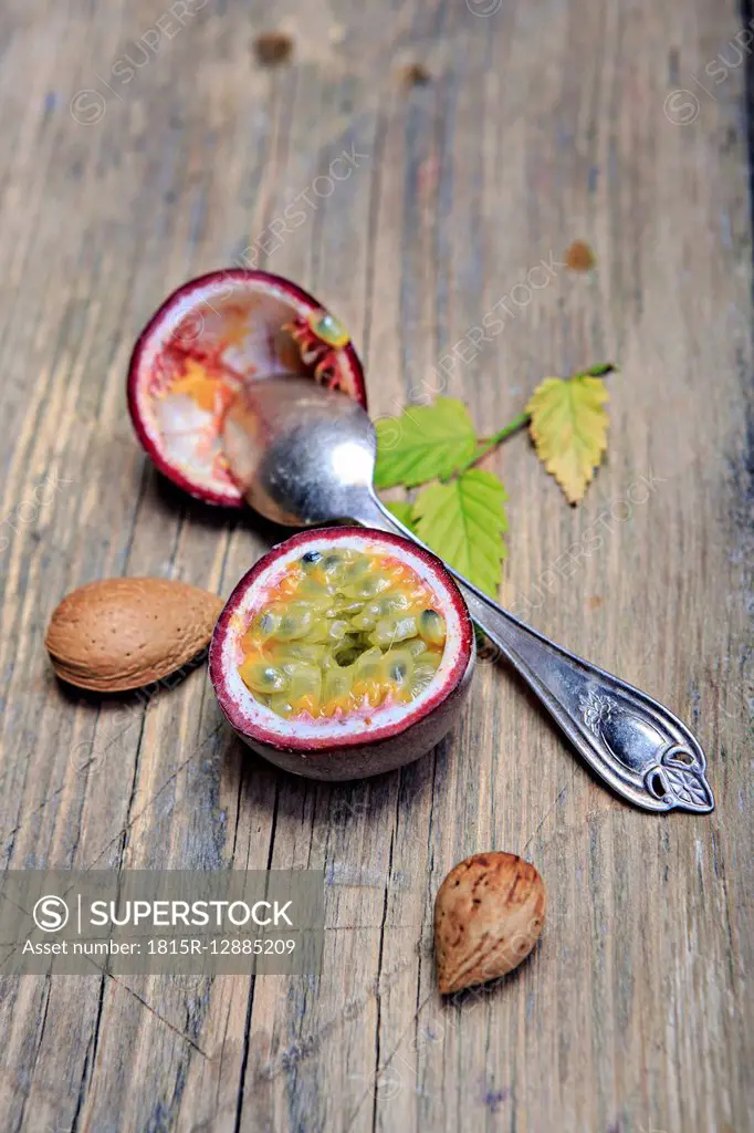 Sliced passion fruit, almonds and silver spoon on wood