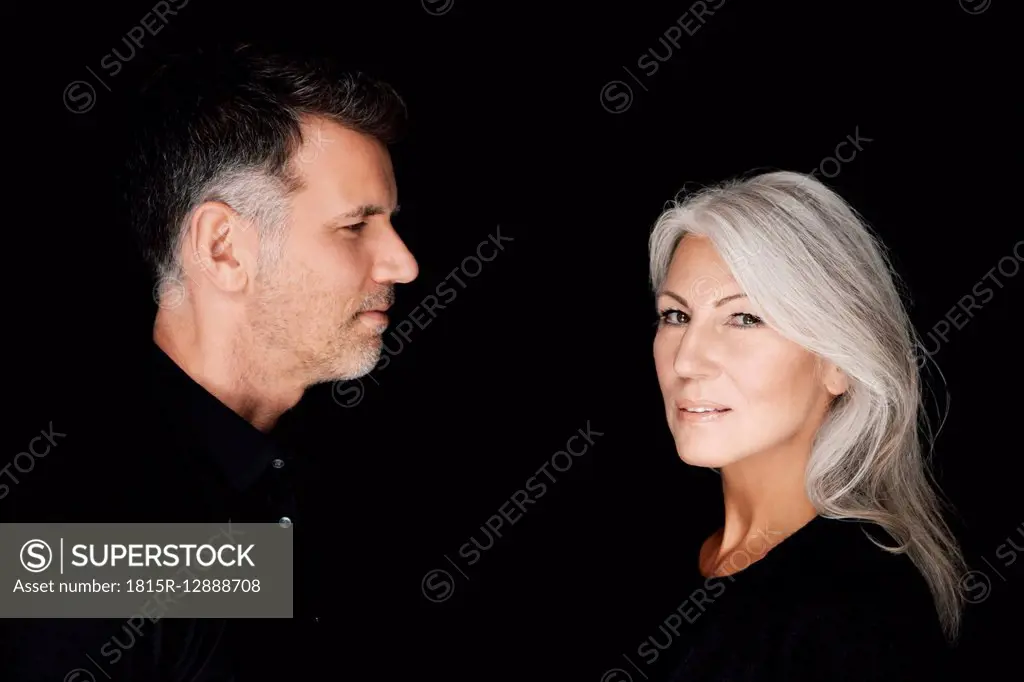 Portrait of mature man and mature woman wearing black clothes in front of black background