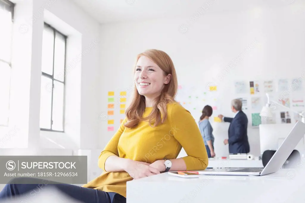 Smiling young woman in office at desk