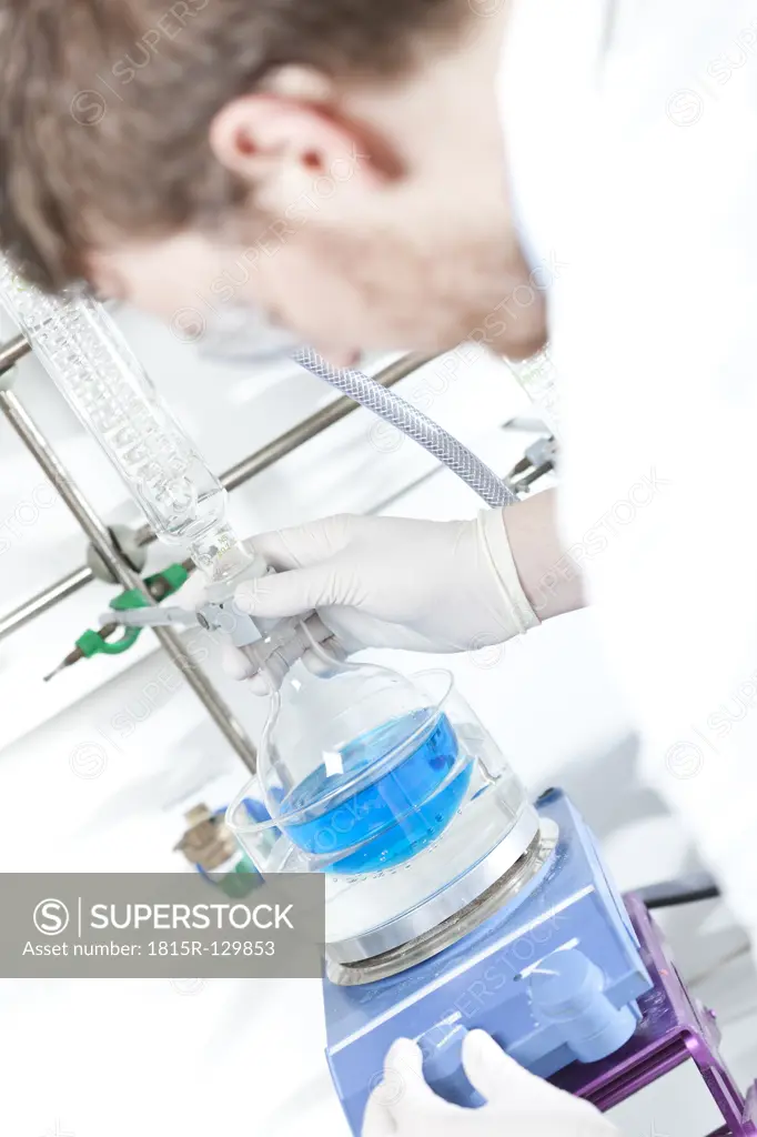 Germany, Young scientist setting up experiment with flask and condenser