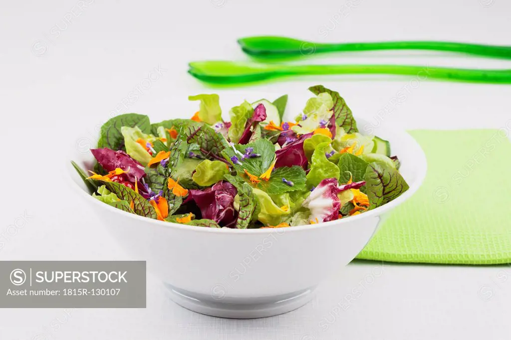 Salad in bowl with napkin and green plastic spoon, close up
