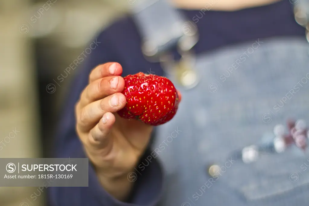 Girl holding strawberry in her hand, close up