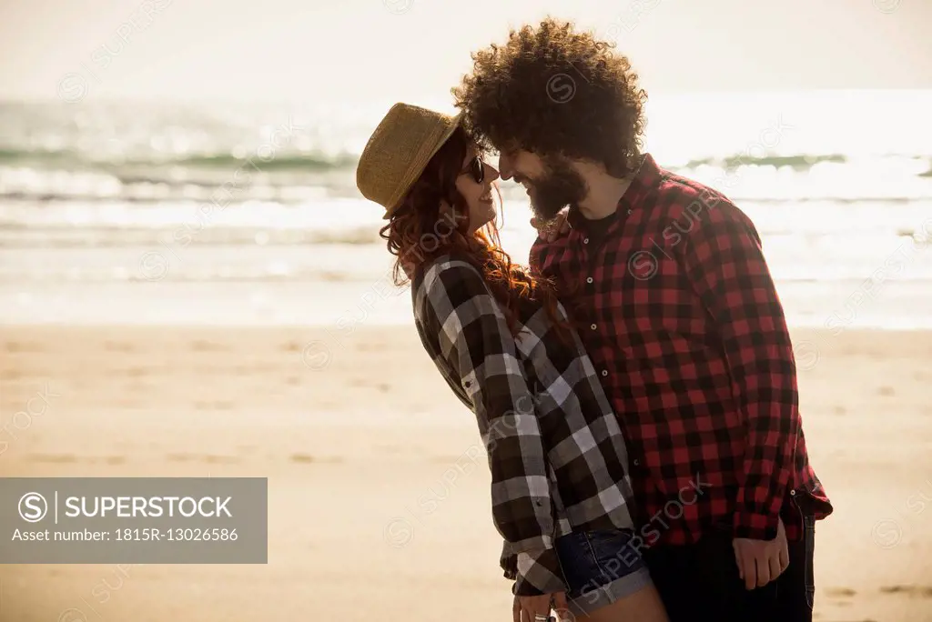 Spain, Cadiz, young couple in love standing face to face on the beach