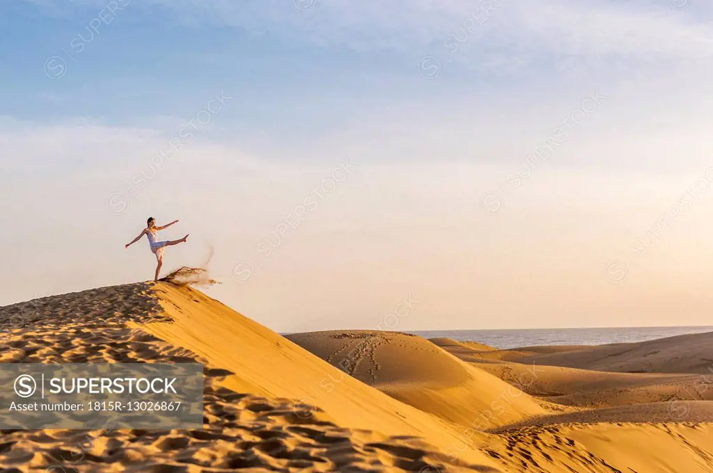 Woman on dune kicking sand
