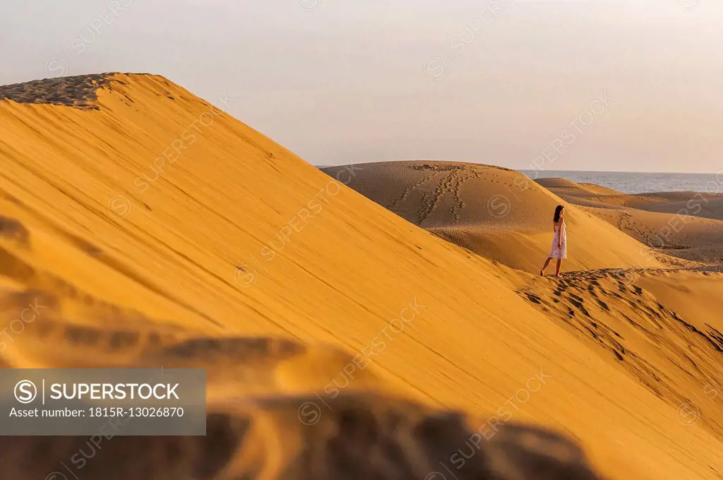 Woman walking over sand dunes