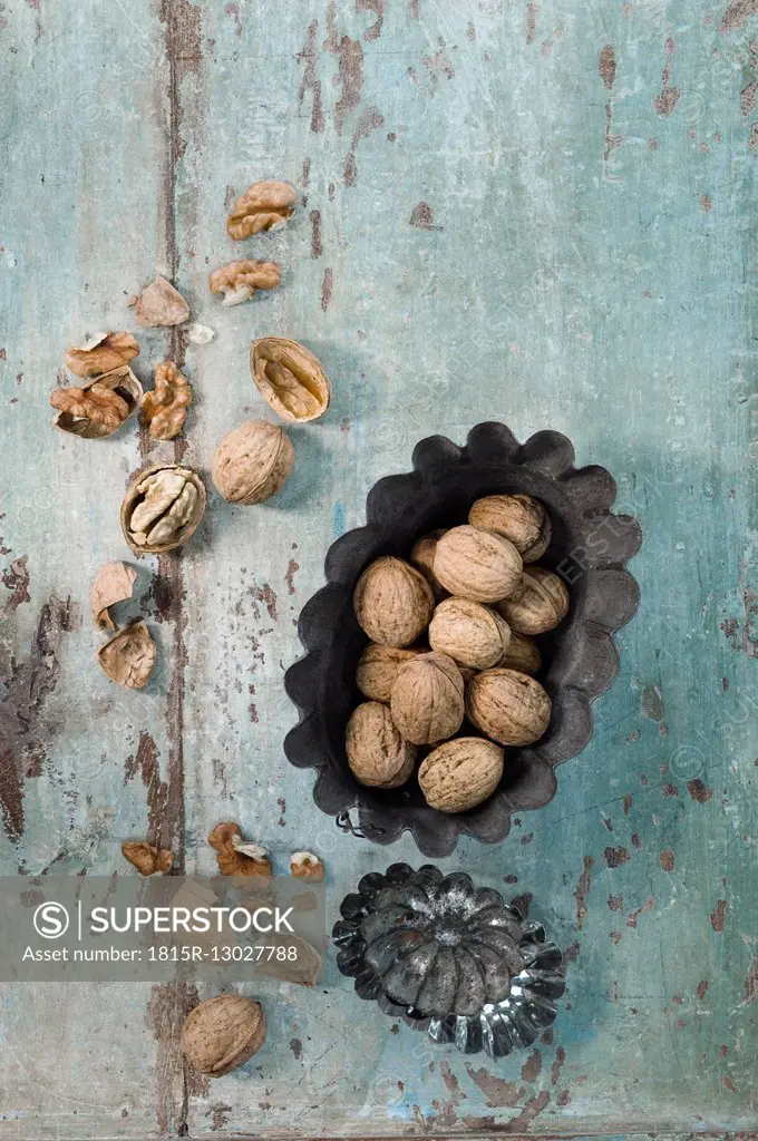Two cake pans and walnuts on wood