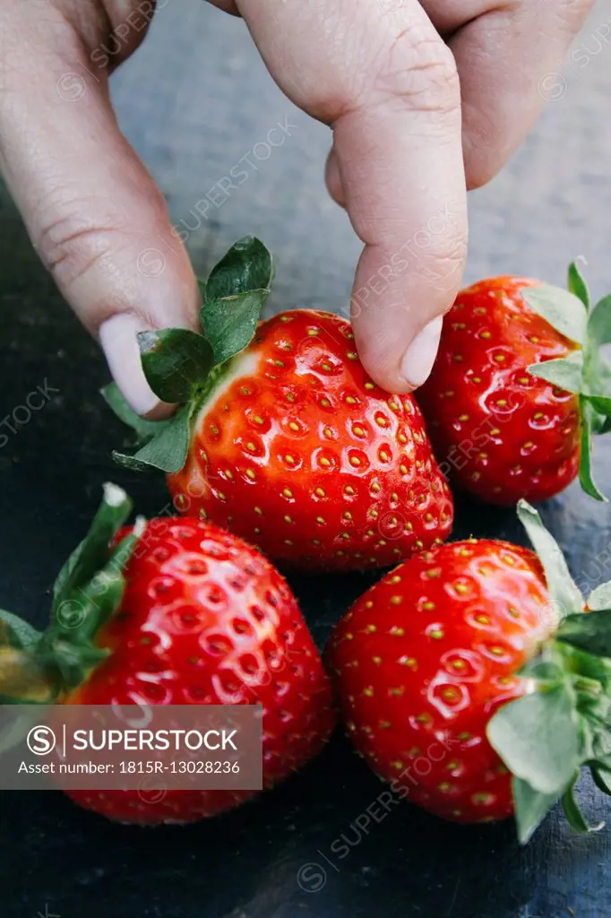 Fingers taking a strawberry