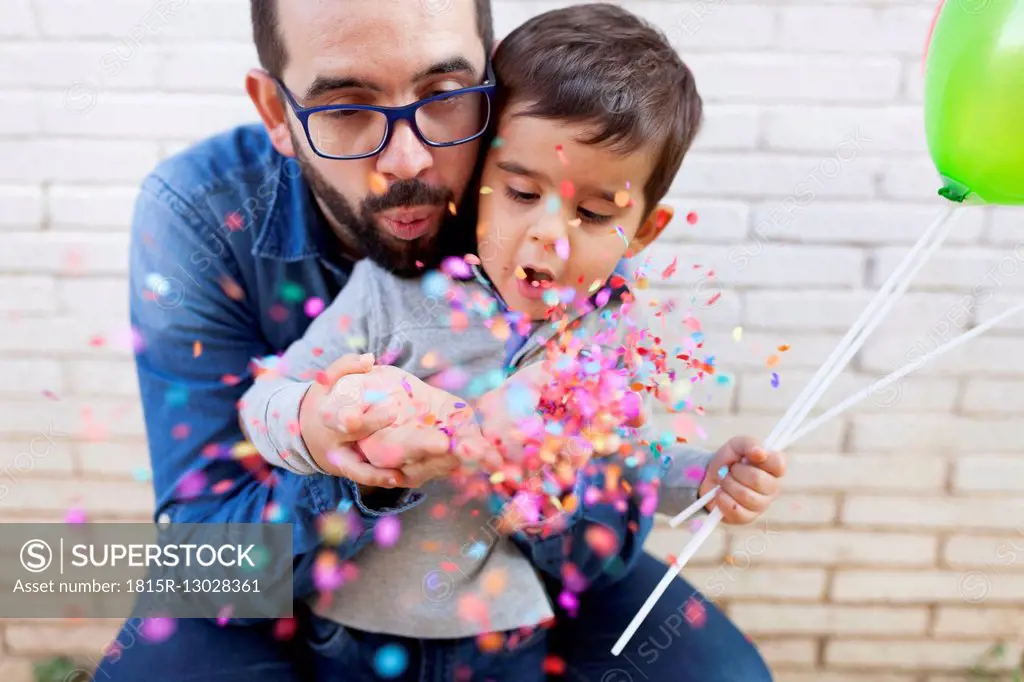 Father and his little son blowing confetti