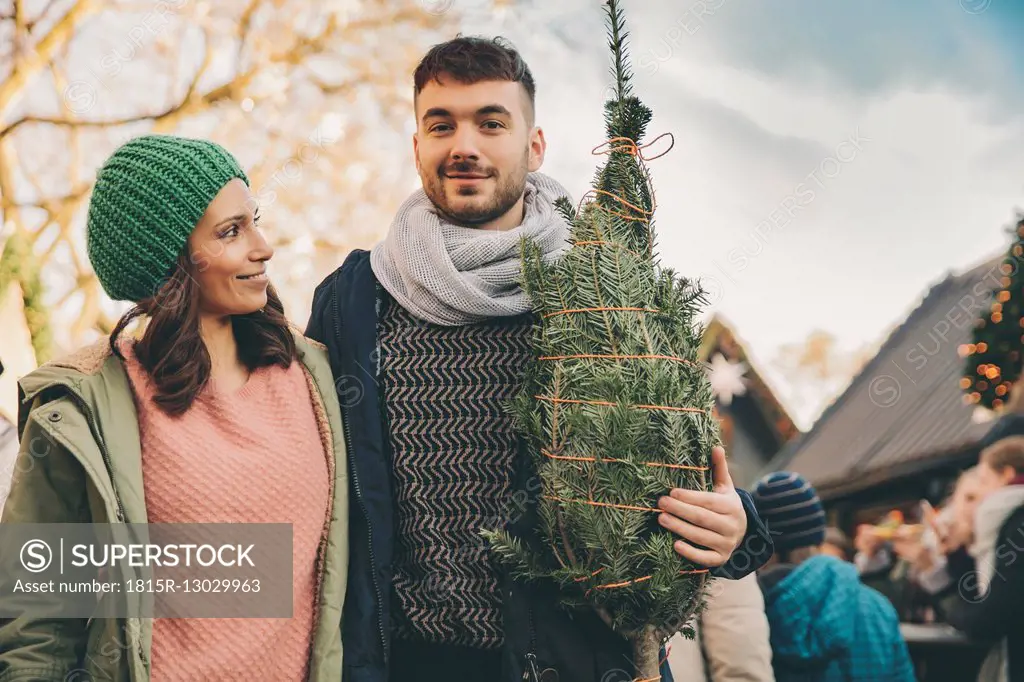 Happy couple with a tree on the Christmas Market