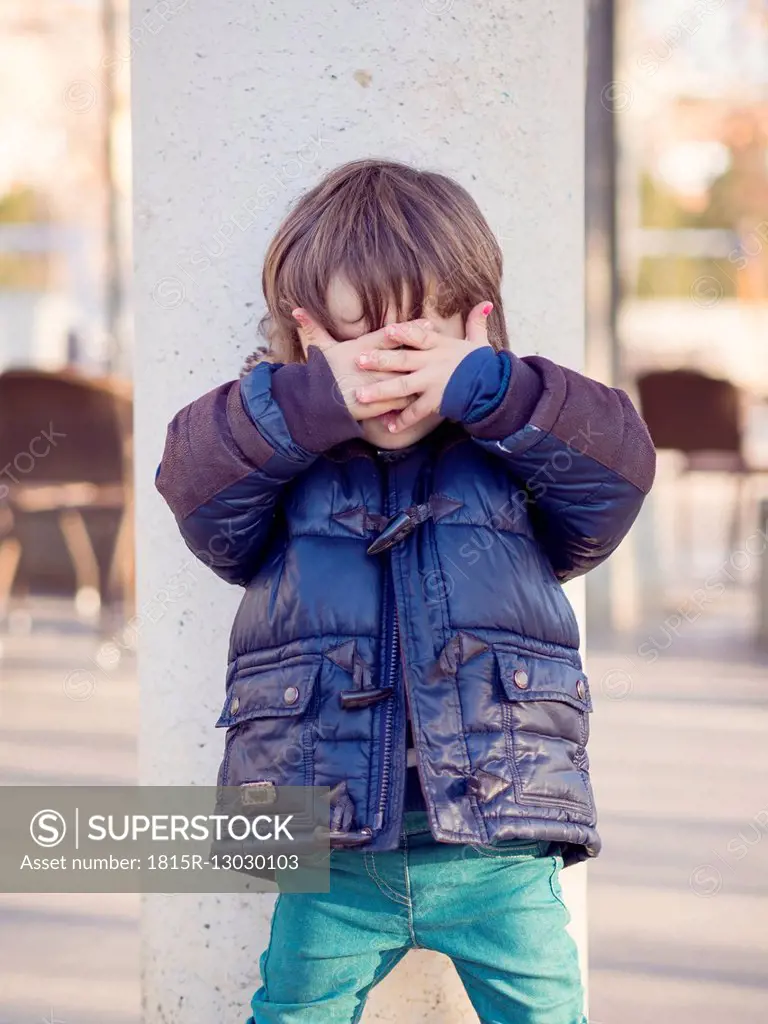 Little boy covering face with his hands