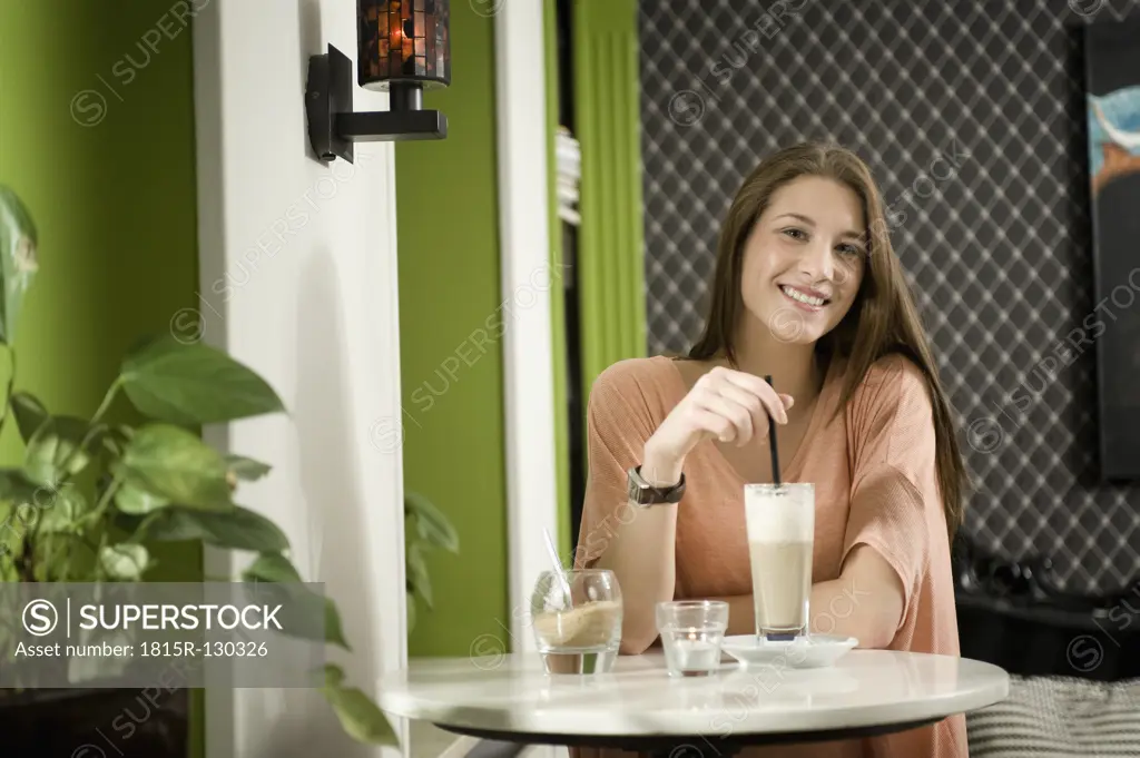 Germany, Bavaria, Munich, Portrait of young woman sitting in cafe, smiling