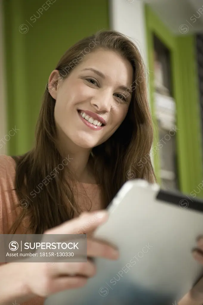 Germany, Bavaria, Munich, Portrait of young woman using digital tablet, smiling