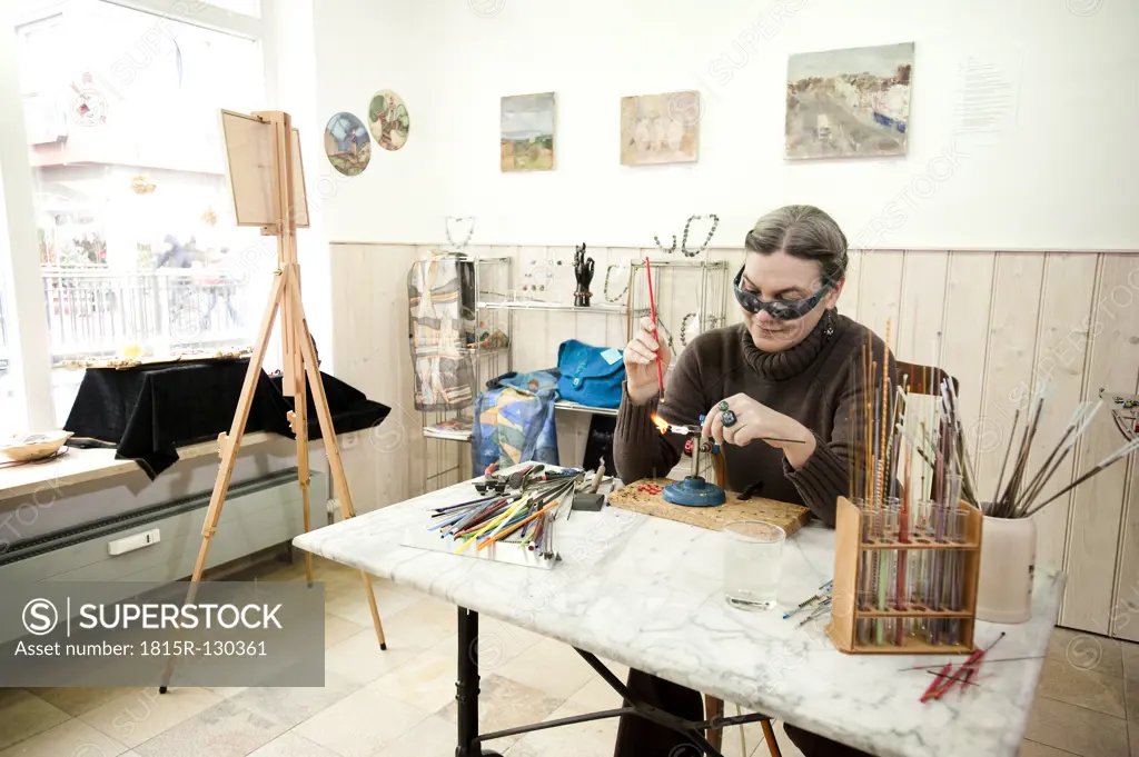 Germany, Bavaria, Mature woman making glass beads