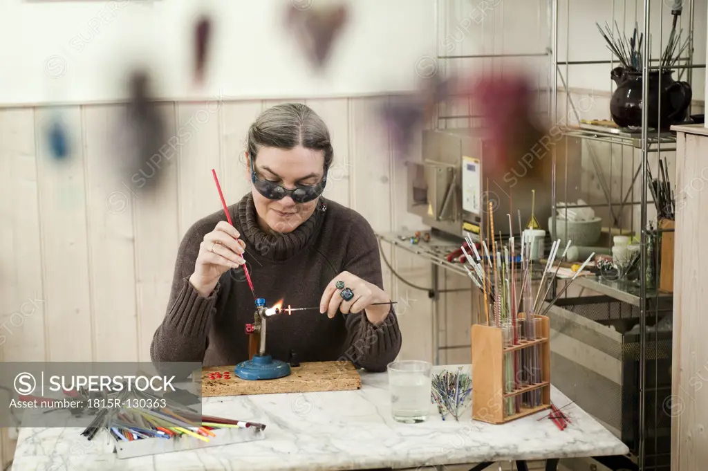 Germany, Bavaria, Mature woman making glass beads