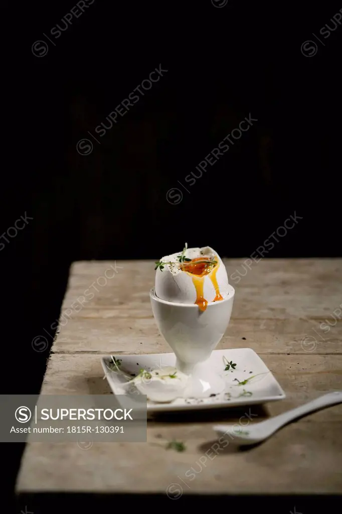 Cracked egg in egg cup with cress and spoon, close up