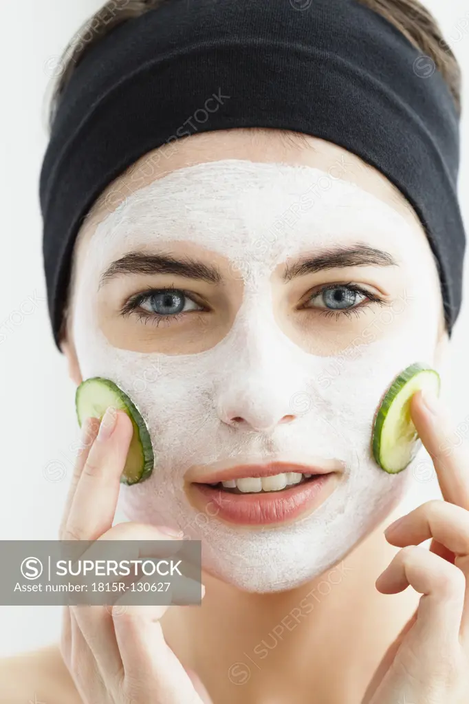 Germany, Bavaria, Munich, Portrait of young woman with cucumber mask, close up