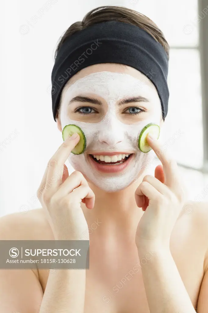Germany, Bavaria, Munich, Portrait of young woman with cucumber mask, close up