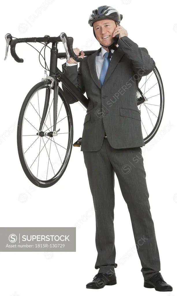 Business man talking on mobile phone and carrying bicycle