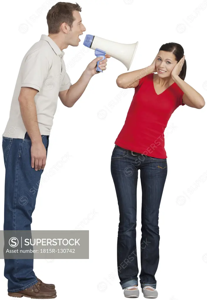 Mid adult man with megaphone shouting on young woman