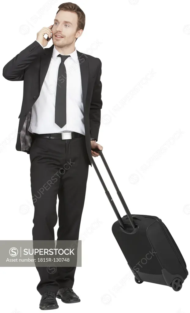 Mid adult businessman talking on phone and holding trolley
