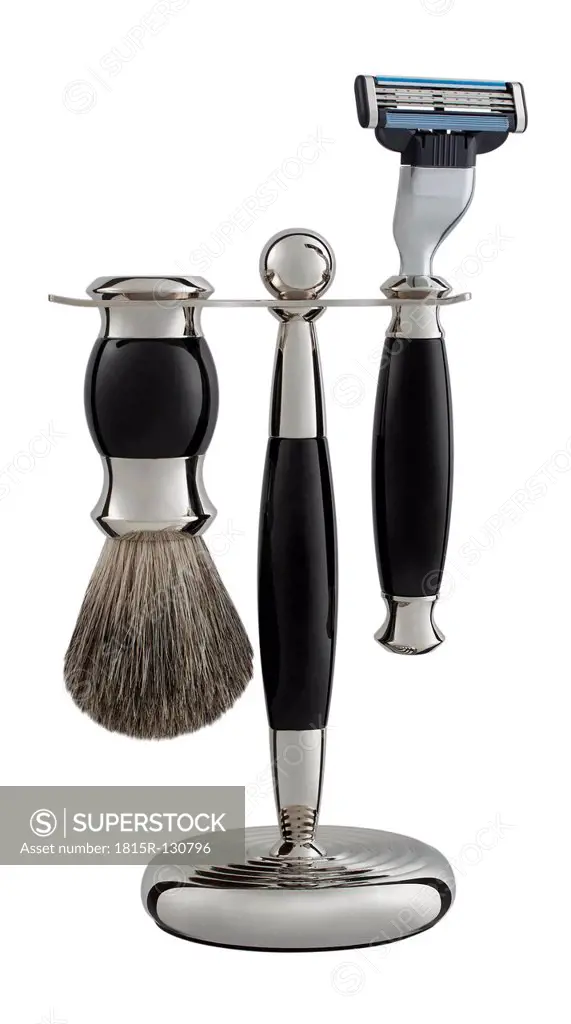 Razor and shaving brush in stand on white background, close up