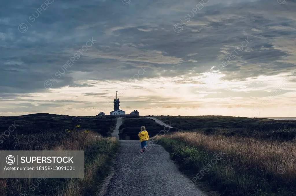 France, Brittany, Pointe du Raz, boy walking towards lighthouses Phare de la Vieille and Phare de Tevennec