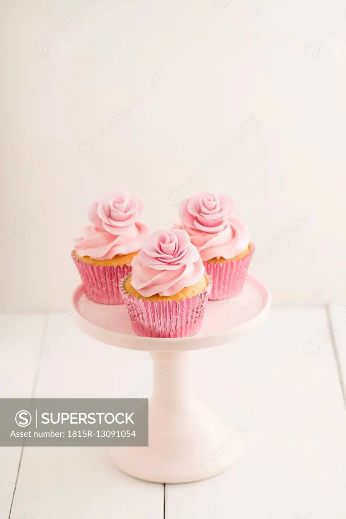 Three pink cup cakes on a cakestand