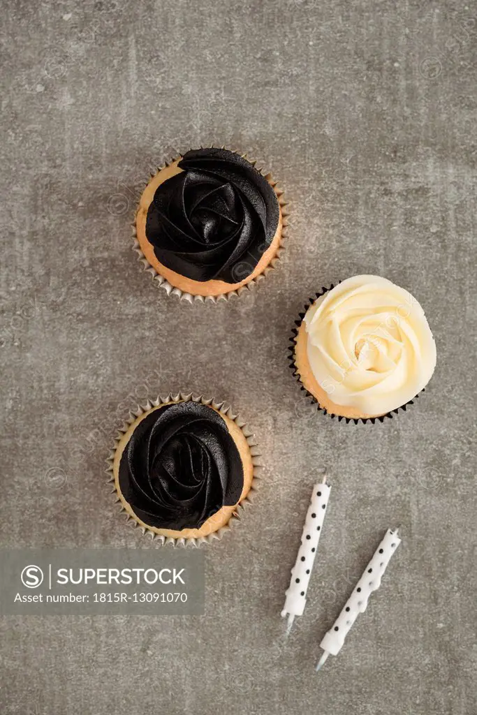Cup cakes with black and cream coloured buttercream topping and two candles