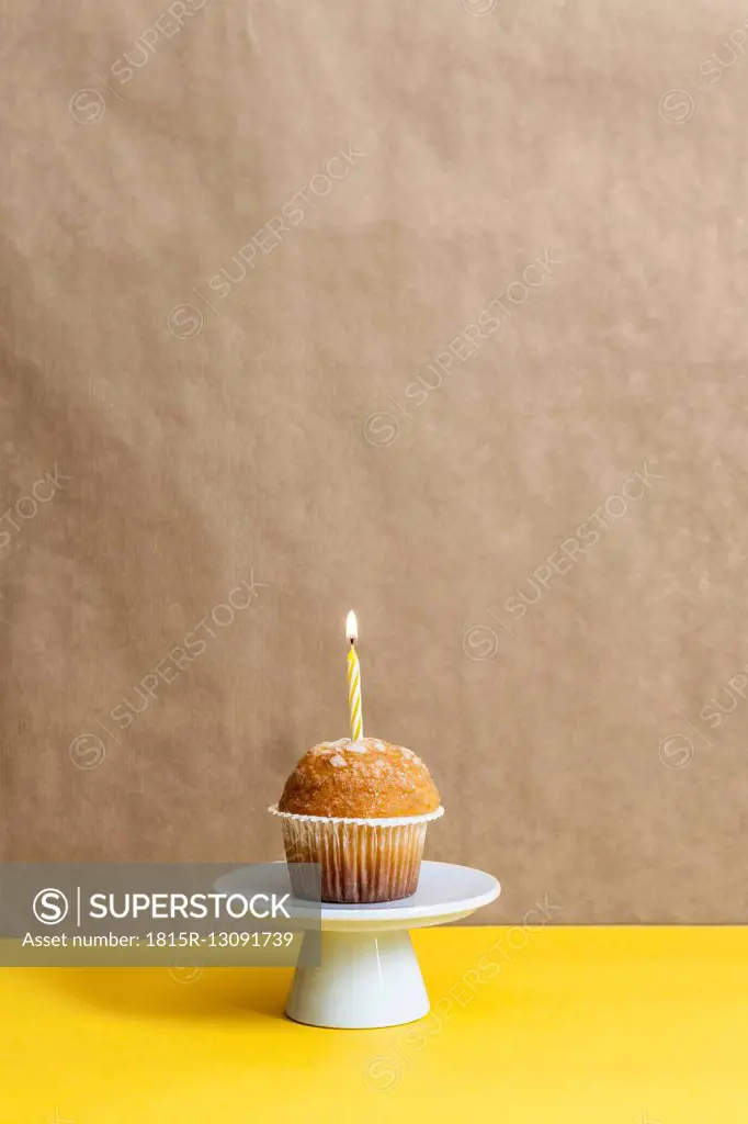 Muffin with lighted candle on a cake stand
