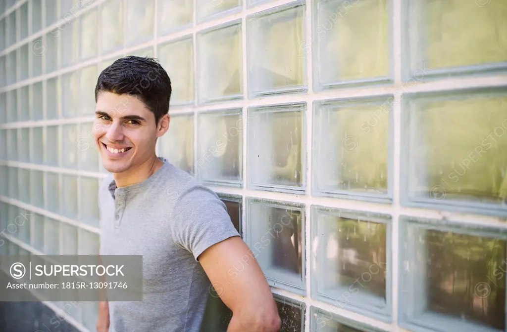 Portrait of smiling young man standing in front of wall