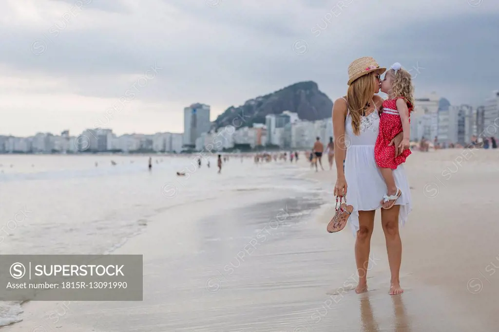 Brasil, Rio de Janeiro, mother carrying and kissing daughter on Copacabana beach