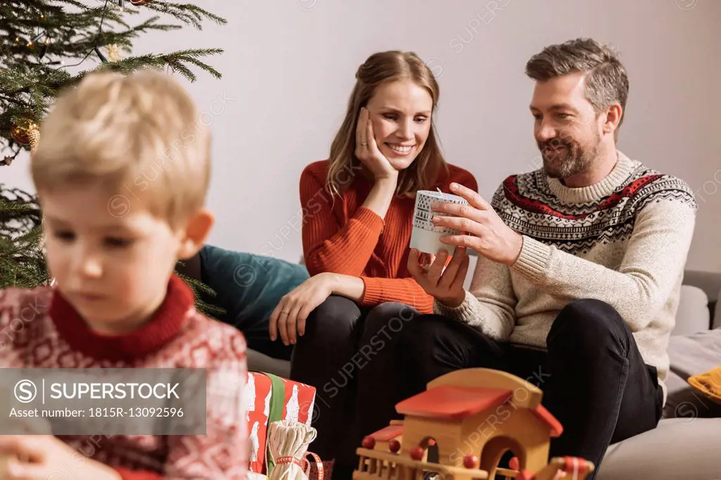 Parents exchanging a Christmas gift on sofa