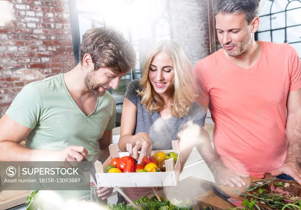 Friends in kitchen looking at crate with tomatoes