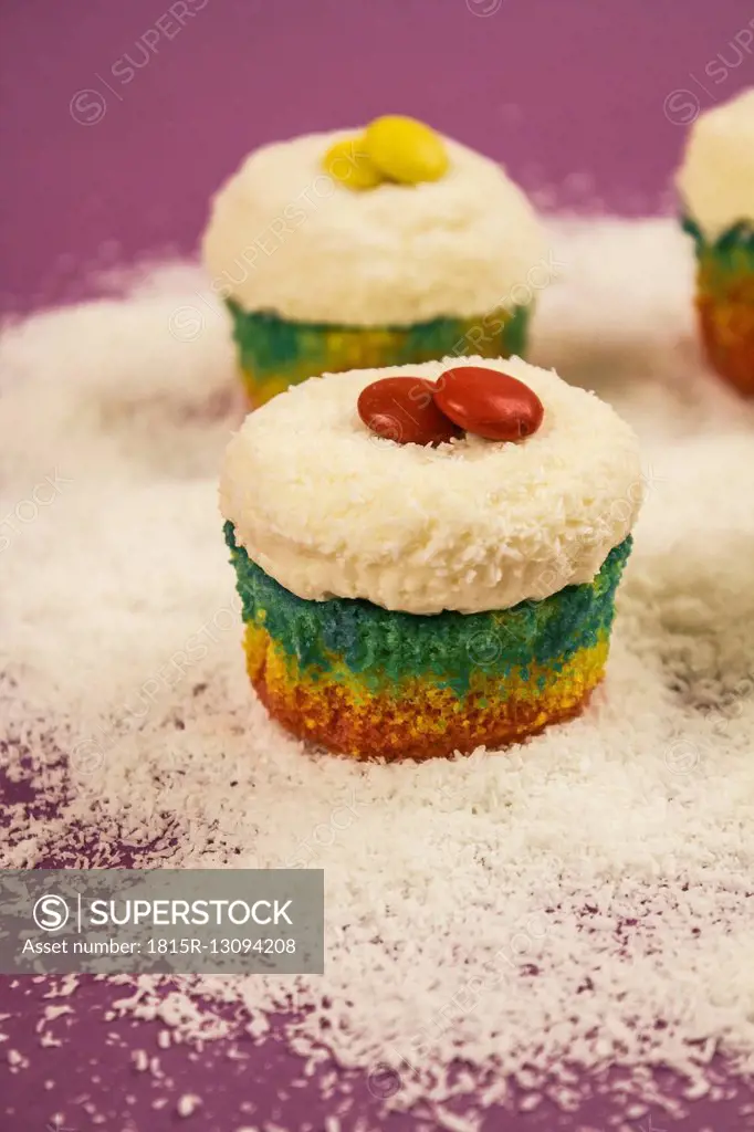 Cupcakes in prismatic colours sprinkled with grated coconut