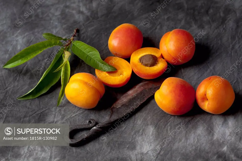 Apricots with leaves and knife on black textile, close up