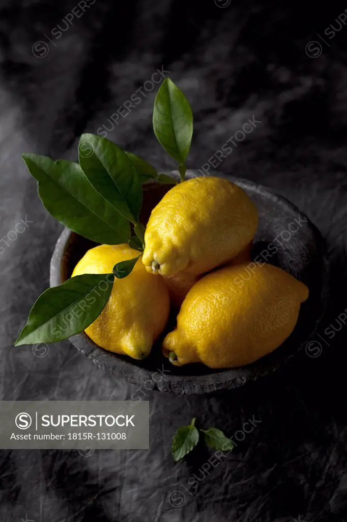 Bowl of lemons and leaves, close up