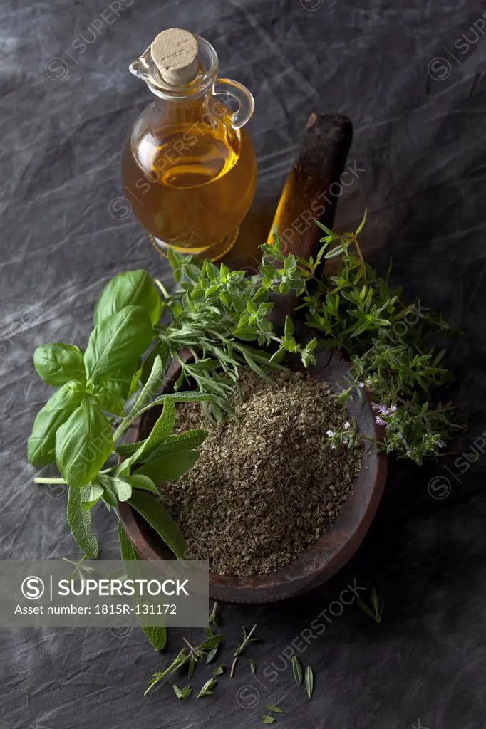 Variety of Italian herbs and powder in wooden spoon with olive oil, close up