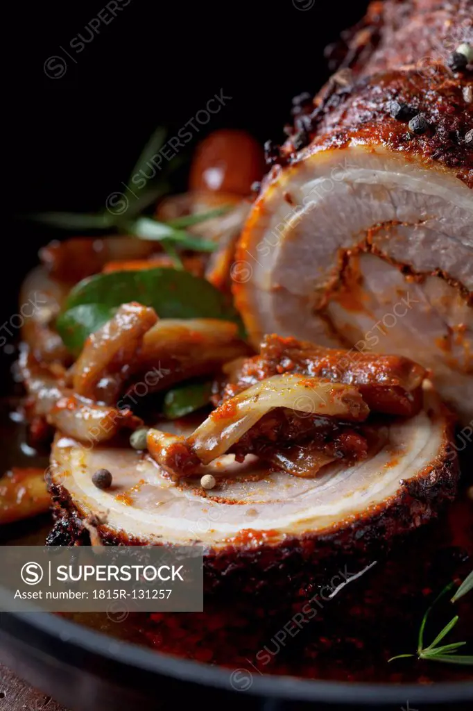 Rolled roast pork and braised vegetables in frying pan, close up