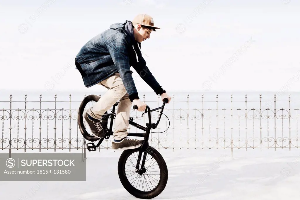 Germany, Schleswig Holstein, Teenage boy jumping with BMX bike