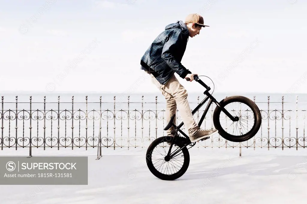 Germany, Schleswig Holstein, Teenage boy jumping with BMX bike