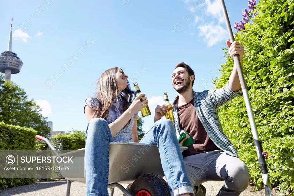 Germany, Cologne, Young couple holding beer bottles, smiling
