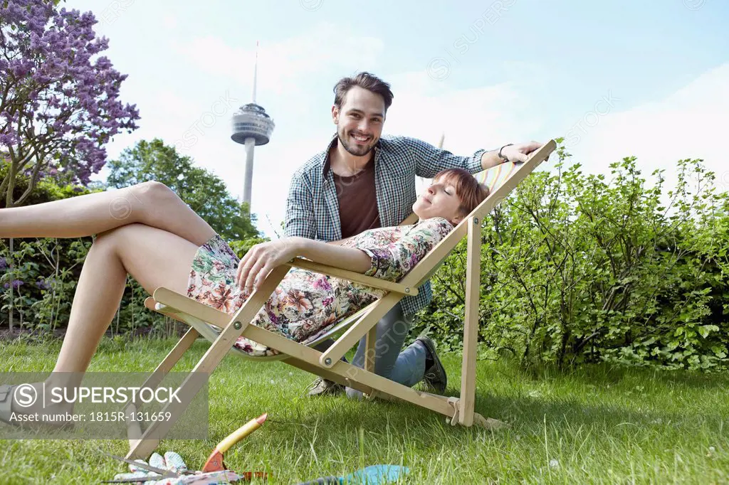 Germany, Cologne, Young couple relaxing in garden, smiling