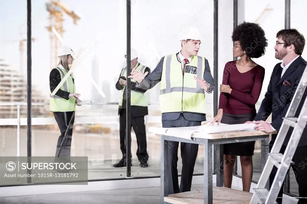 Architect wearing safety vest talking to man and woman